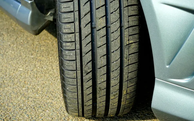Nahaufnahme von Reifenprofil und Radkasten eines silbernen Autos.